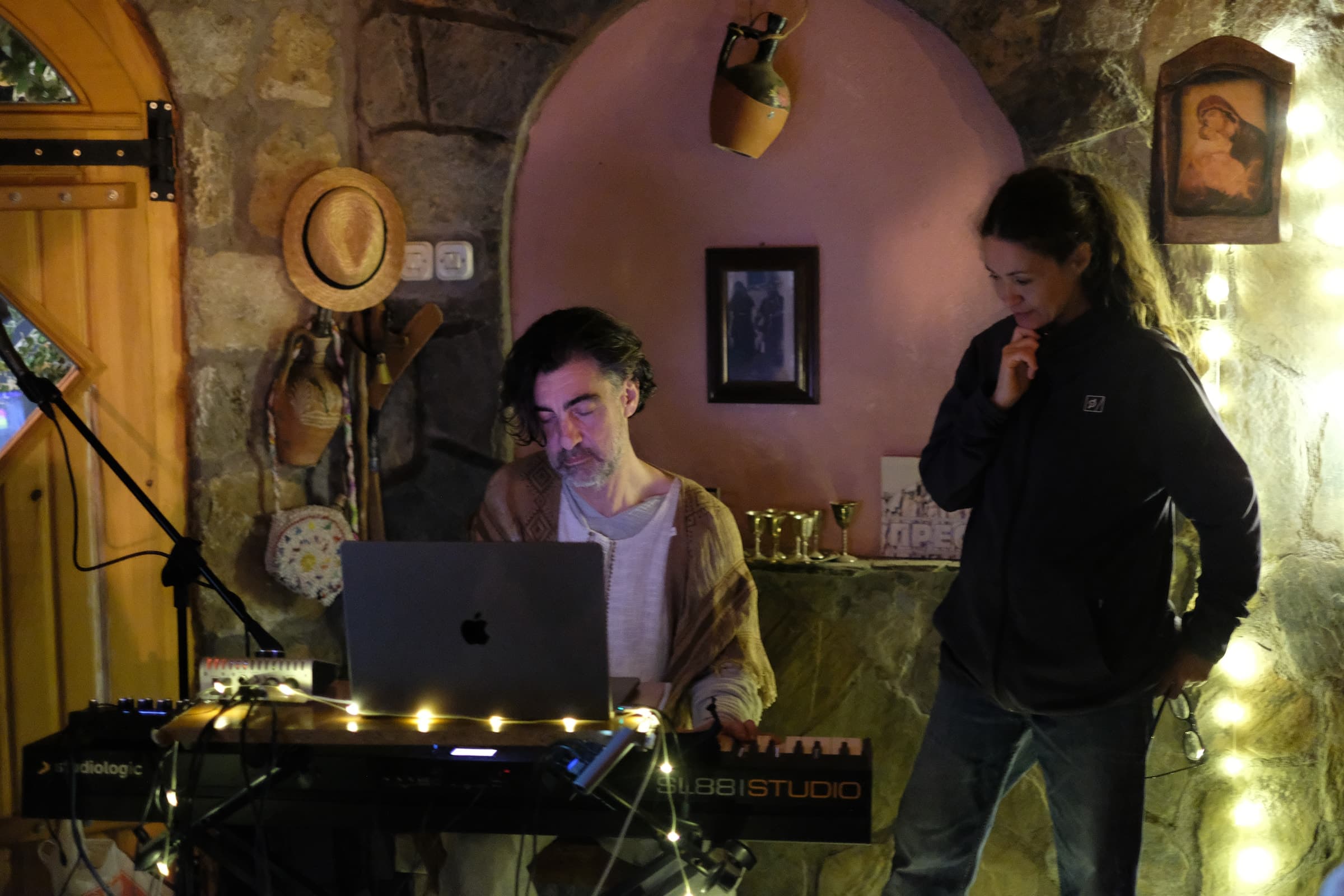 Duke Bojadžiev composing at a keyboard and laptop during a Resonance Atelier session, with a participant nearby.
